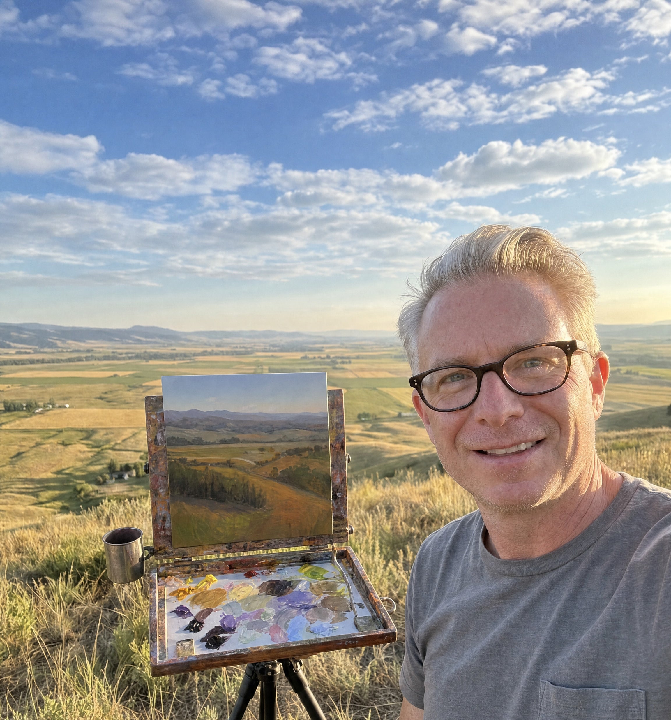 Jeremy Vlcan painting on location, pochade box and palette on a hillside